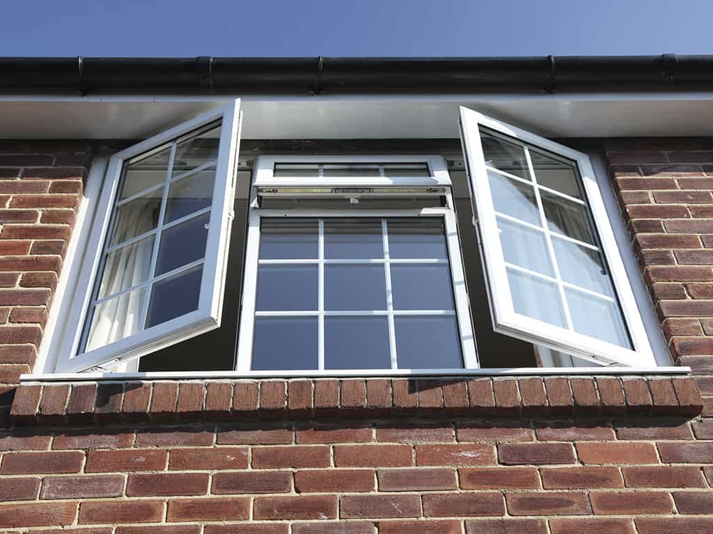 A window in a brick house with a white aluminum frame.