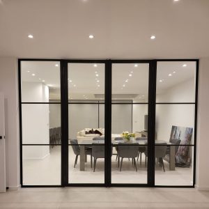 A dining room with glass doors featuring the ID30 Internal Door and fixed glazing system.