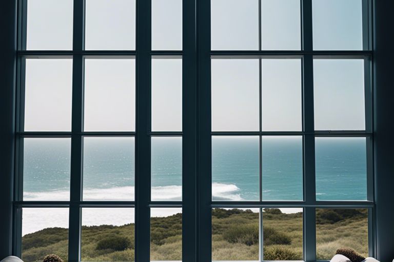 Two people looking out of a window at the ocean.